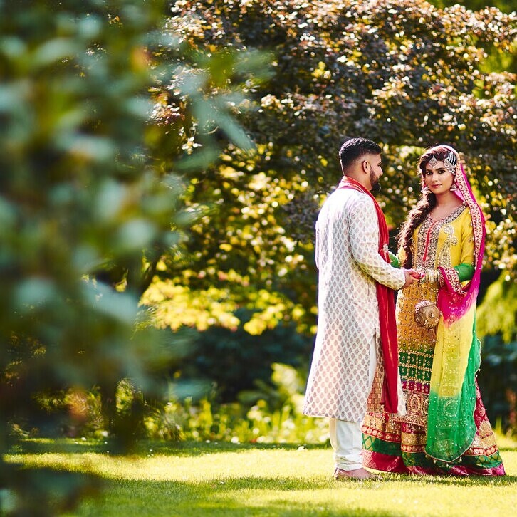 Bryllupsbillede af pakistansk par, i grønne omgivelser