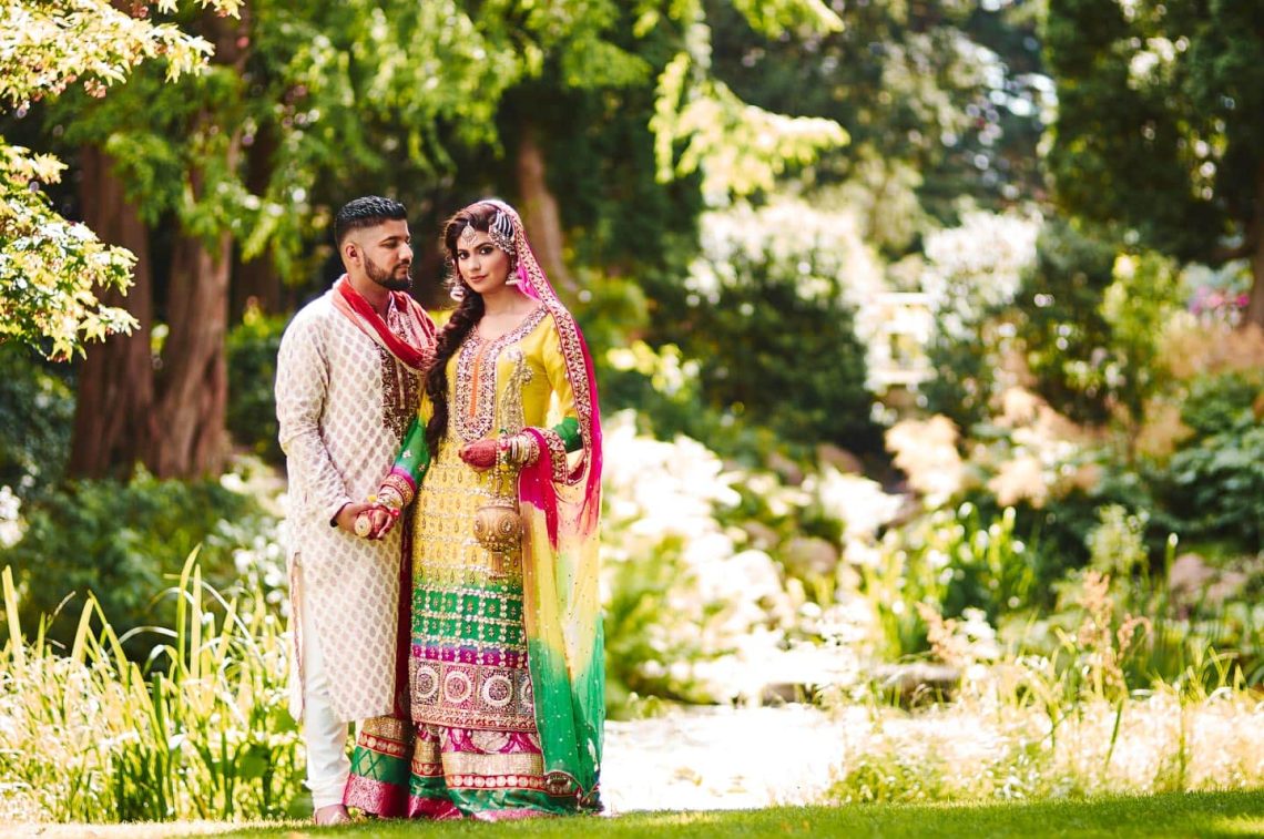Bryllupsbillede af pakistansk par, i grønne omgivelser