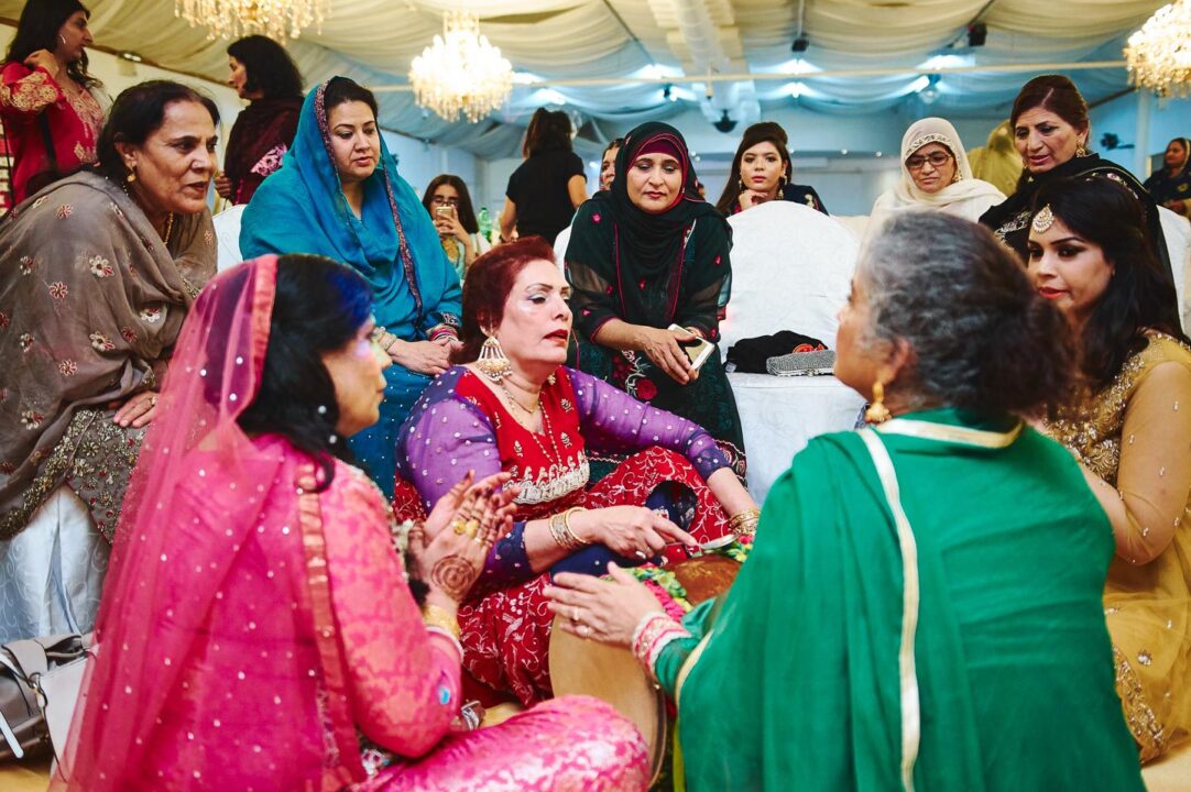 Bryllupsfotograf pakistansk: Kvinder synger og spiller på tromme, under pakistansk bryllup/menhndi